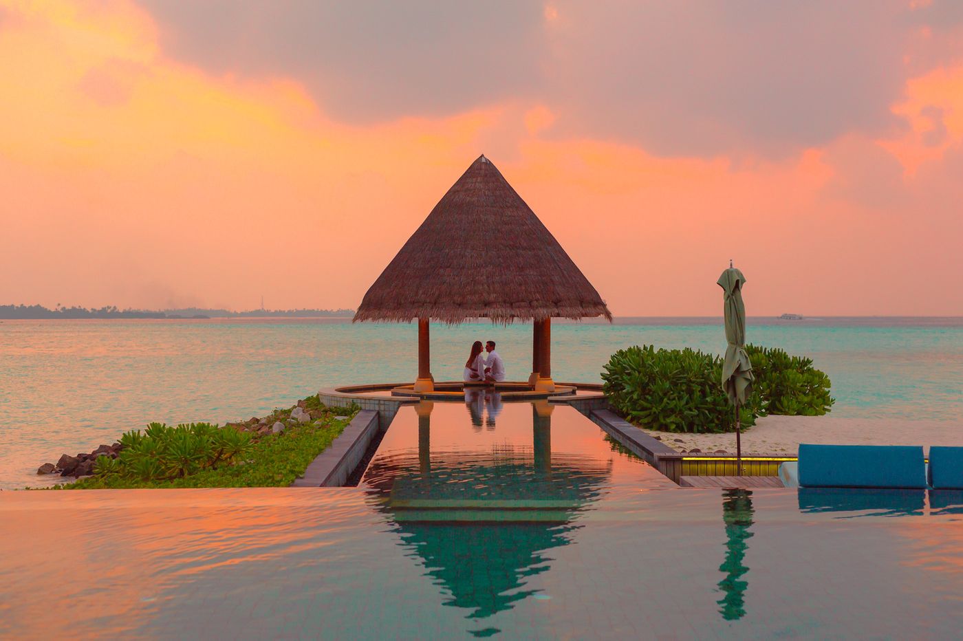 Couple romantic moment by sea under beach cabana at sunset